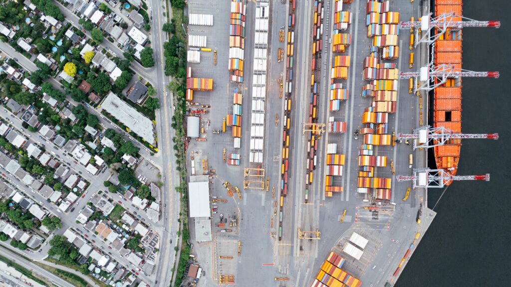 Aerial view of shipping containers and cranes at a port beside a residential neighbourhood